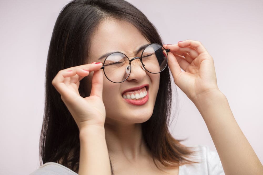 A young woman squints through her glasses and considers getting eye surgery to correct her vision - either LASIK or PRK.