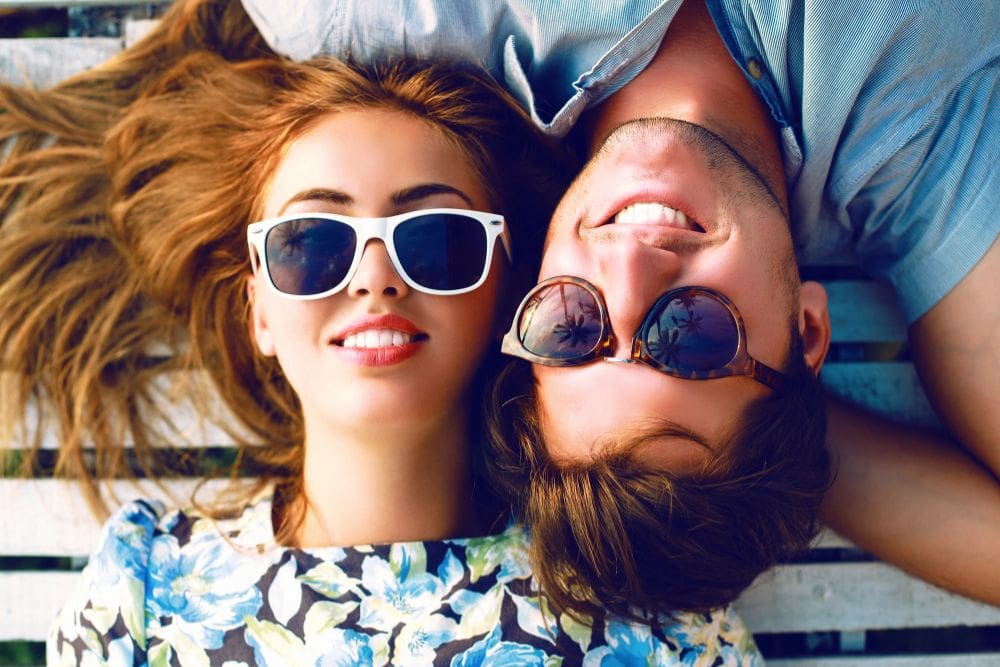 A young man and woman wearing sunglasses smile at the camera after having LASIK in Atlanta. 